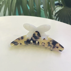 Detail of tortoise shell acetate hair claw with delicate white butterfly ornament