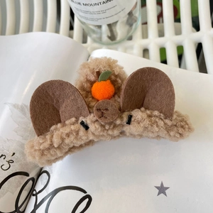 Pince à cheveux ours en peluche marron avec détail orange sur un magazine