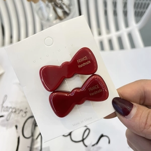 Macro shot of two burgundy bow hair clips with gold France Handmade lettering on a card