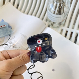 Détail d'une mini pince à cheveux monstre Y2K avec œil de dessin animé et étoiles