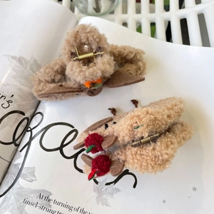 Pinces à cheveux de Noël en peluche avec pompons cerises sur un fond de magazine épuré