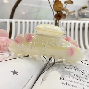 Dettaglio ravvicinato della grande pinza per capelli in acetato con cuori rosa e perline