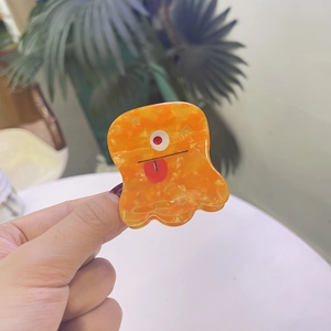 Gros plan détaillé d'une mini pince à cheveux monstre orange avec une drôle d'expression
