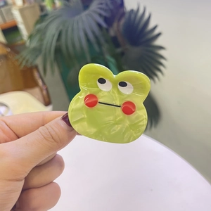 Gros plan détaillé d'une mini pince à cheveux monstre vert en matériau acétate de y2k