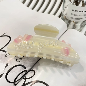 Dettaglio molletta per capelli in resina crema con cuore rosa e scritte di perle miss you