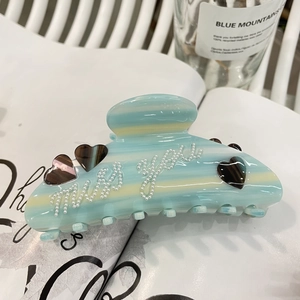 Dettaglio della pinza per capelli in acetato a righe blu con scritta miss you in perle