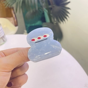 Vue détaillée d'une pince à cheveux bleue à texture marbrée tenue dans la main