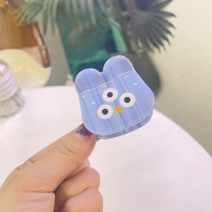 Détail de la pince à cheveux monstre bleu en acétate avec texture marbrée et design à trois yeux