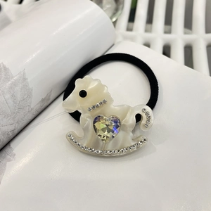 Close-up of cream white Trojan horse hair tie with large heart-shaped crystal on black band