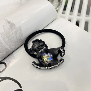 Close-up of black elastic hair tie with frosted horse charm and iridescent heart crystal