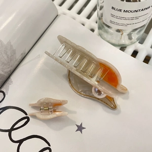 Détail du set de pinces à cheveux en acétate marbré crème avec décoration en perle