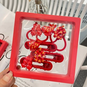 Festive red Chinese New Year hair clip set with koi and firecracker designs in a display box