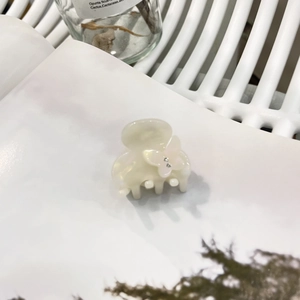 Dettaglio del fermaglio per capelli in acetato crema con una farfalla rosa e strass lucidi