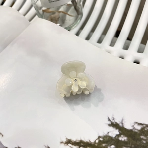 Elegante molletta per capelli in acetato bianco crema con strass floreali su rivista