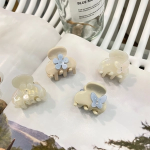 Dettaglio di mini mollette per capelli in acetato con design a fiori e farfalle