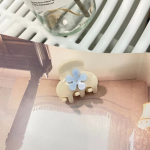 Dettaglio molletta in acetato crema con fiore blu e cristallo su rivista vintage