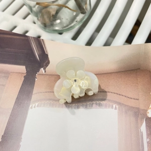 Dettaglio dell'elegante molletta per capelli a fiore in acetato bianco perla con strass