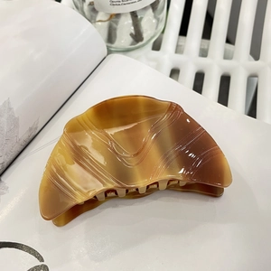 Detailed view of the amber croissant hair claw clip resting on a white magazine background
