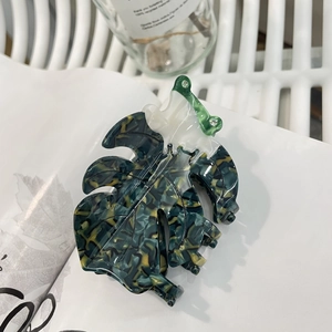 Macro d'une grande pince à cheveux Monstera en acétate marbré vert avec détail en strass