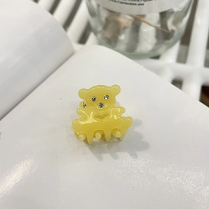 Vue macro d'une mini pince à cheveux ours jaune en acétate ornée de strass en cristal brillant
