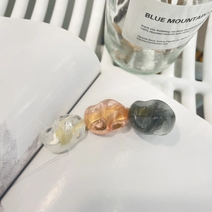 Tre fermagli per capelli in resina ambrata nei colori pesca e grigio su un libro
