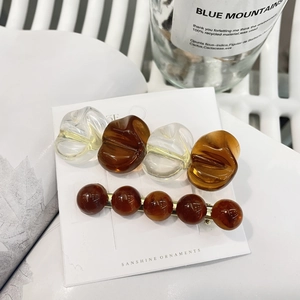Set elegante di fermagli per capelli in resina ambrata e clip dorate su carta bianca