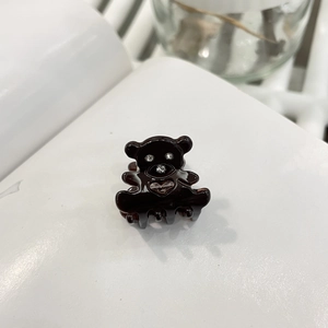 Vue macro détaillée d'une pince à cheveux ours brun en acétate avec des accents de cristal