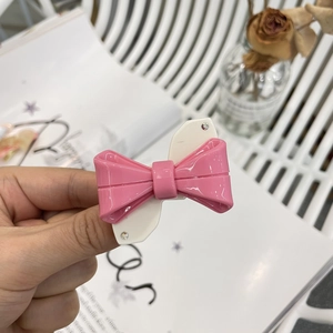 Fermaglio per capelli Y2K in acetato con fiocco rosa e bianco e strass in mano