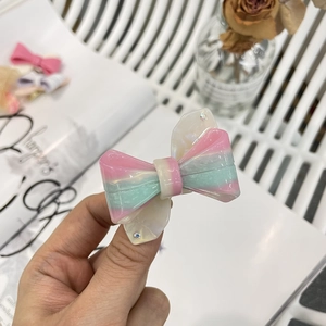 Dettaglio del fermaglio per capelli a fiocco in acetato sfumato rosa con strass Y2K