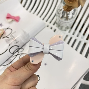 Dettaglio di un fermaglio per capelli a fiocco Y2K in acetato multistrato con strass