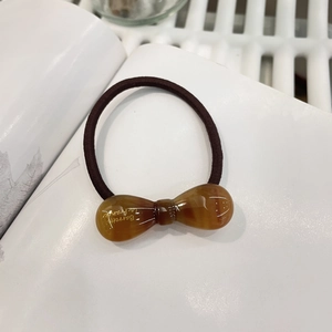 Détail de l'élastique à nœud en résine marbrée ambre avec lettrage Barrette doré