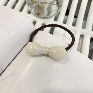 Détail de l'élastique à cheveux avec nœud en résine aspect marbre et cordon marron