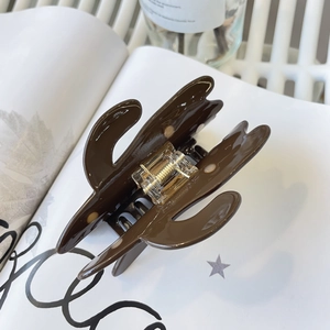 Gros plan d'une pince à cheveux en acétate marron foncé brillante posée sur un magazine