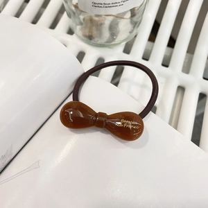 Détail d'élastique nœud en résine ambre avec texte doré Barrette La France