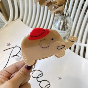 Dettaglio molletta per capelli a forma di elefante in acetato beige con cappello rosso