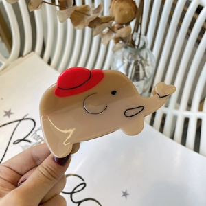 Dettaglio della pinza per capelli a elefante in acetato beige con design a cappello rosso