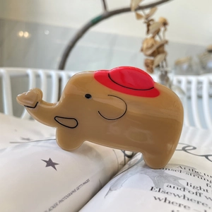 Molla per capelli a forma di elefante in acetato marrone e rosso su un libro