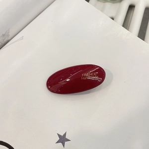 Close-up of deep red acetate hair clip with gold France Handmade lettering detail