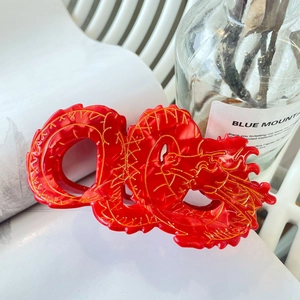 Detailed close-up of a red acetic acid dragon hair claw clip with golden outlines