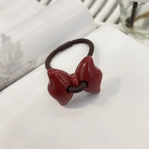 Detail of a vintage red bow hair tie with glossy finish on a white book page