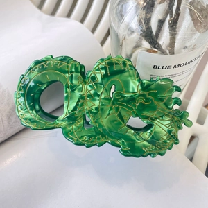 Translucent green dragon hair claw clip with golden scales and minimalist aesthetic