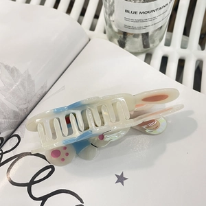 Détail d'une pince à cheveux lapin en acétate blanc avec des oreilles bleues et roses