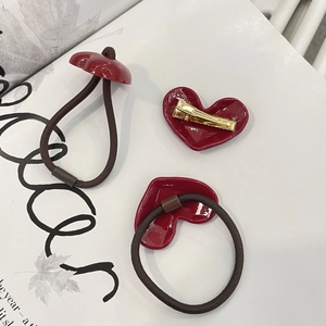 Close-up of red heart hair clips and elastic ties set on minimalist magazine background