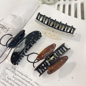 Detailed view of acetate hair claws in black, white, and tortoise shell with rhinestones