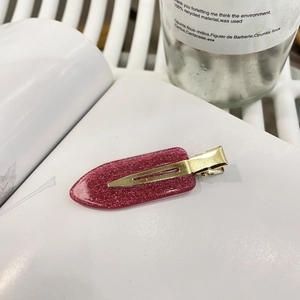 Glitzernde rosa Haarklammer mit goldener Metallbasis auf minimalistischem Hintergrund