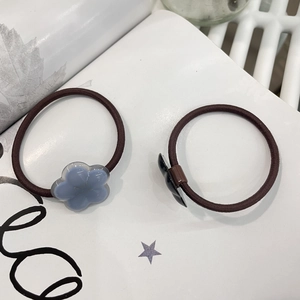 Detailed view of two elastic hair ties featuring blue and black resin floral charms