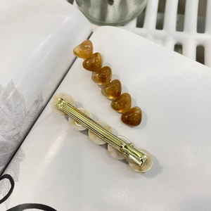 Detailansicht der Bernstein-Herz-Haarspange und der Marmor-Haarclip mit goldener Basis