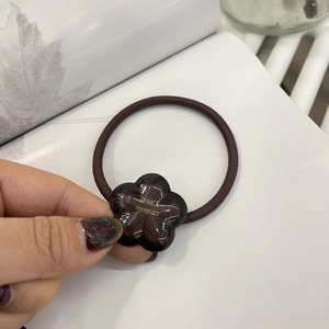 Detailed close-up of brown resin flower hair tie with golden handmade lettering