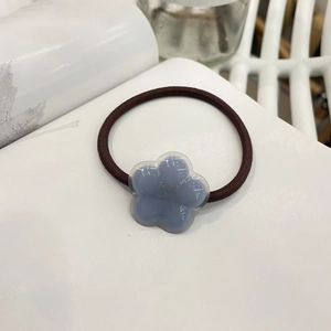 Detail of blue acrylic flower hair tie with gold France Handmade text and brown elastic