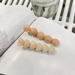 Elegantes Set aus Haarspangen mit Herz und Perlen aus rosa Harz auf goldenem Metallsockel